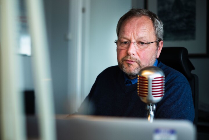 Nils Mehren med mikrofonen han bruker til å lese inn blokker ved arbeidspulten sin. Den har han kjøpt inn som gave til seg selv.