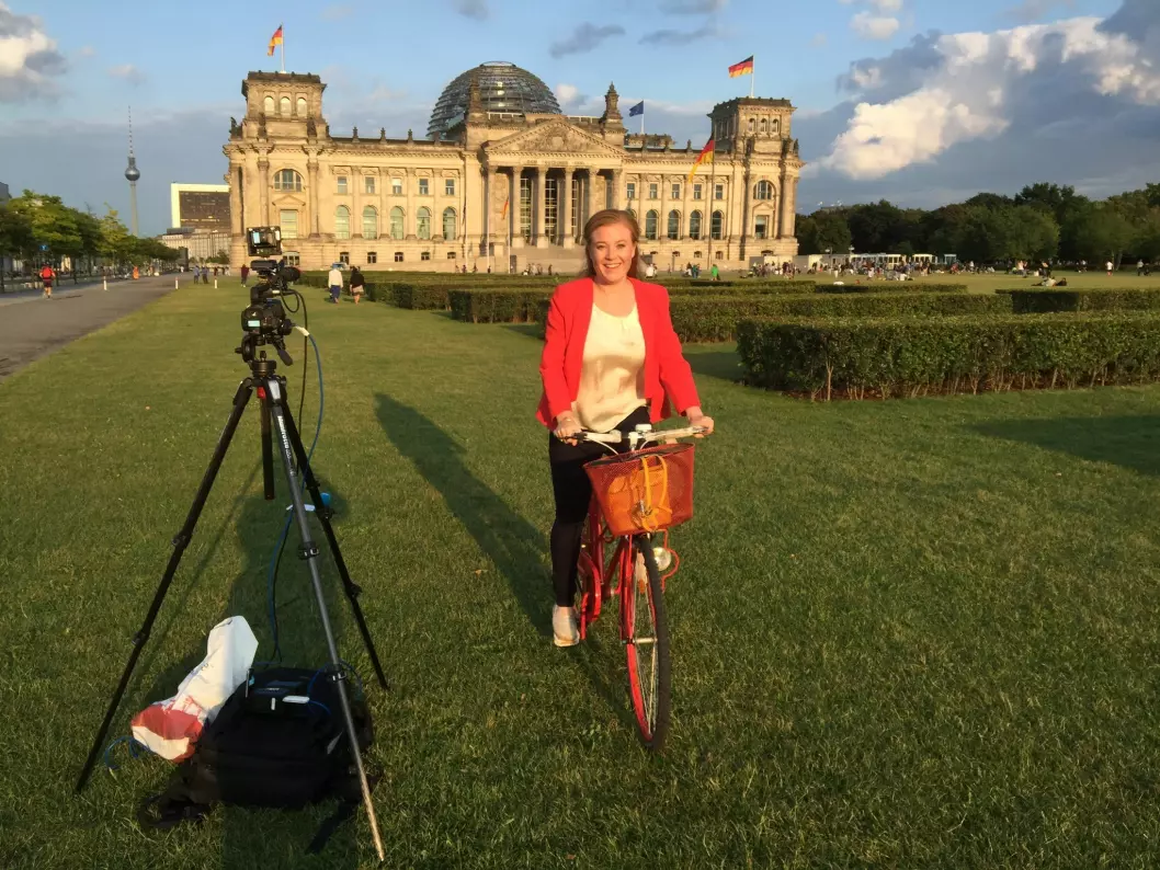 Europa-korrespondent Guri Norstrøm på sykkel utenfor Riksdagsbygningen i Berlin, før en direkterapport i Dagsrevyen. FOTO: NRK