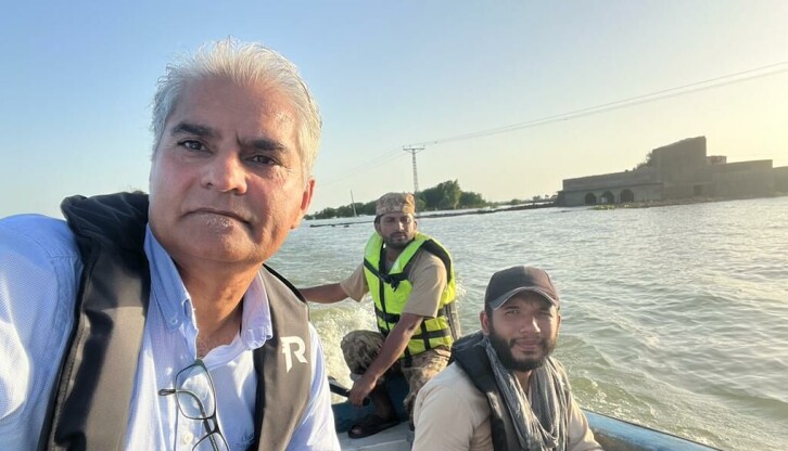 Atta Ansari (til venstre) og hans fotograf Asif Afridi på vei til byen Khaipur Nathan Shah med båt. Under vannet ligger det som vanligvis er motorveien.