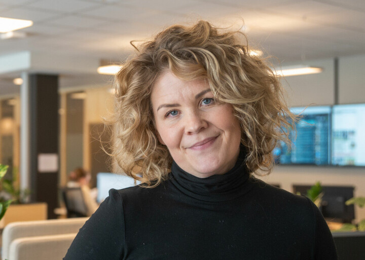 Linn Kristin Djønne er debattredaktør i Laagendalsposten i Kongsberg. Bildet er tatt inne i redaksjonslokalet, med planter og dataskjermer i bakgrunnen.