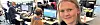 Bilde fra kontorlandskapet. Ei smilende jente i fokus, med to menn sitter med headset og jobber i bakgrunnen.