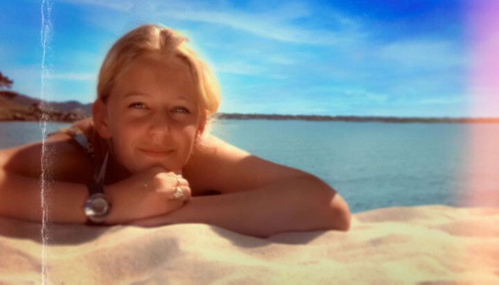Bilde av Tina Jørgensen som ligger på en strand og smiler inn i kamera.