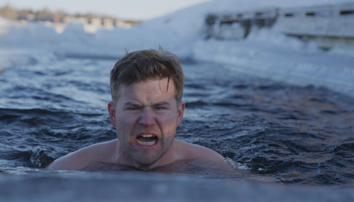 Mann svømmer i veldig kaldt isvann.