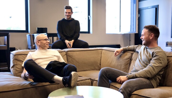 Tidligere VG-ansatte Simen Gjerstad, Jamel Rake og Thor-Erik Claussen. To menn sitter i en sofa og ser på hverandre. En tredje mann sitter bak. Alle smiler.