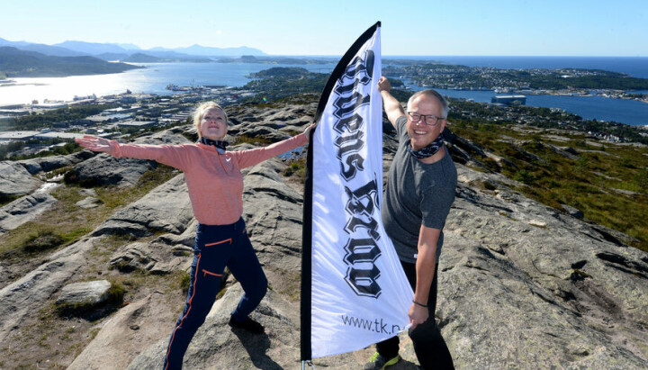 to ansatte fra tidens krav på fjelltopp med logo-flagg