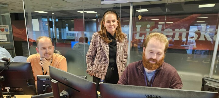 Tre kolleger på kontoret, to menn og en kvinne ser på samme skjerm