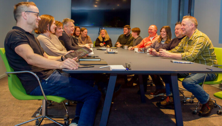 Gruppebilde av kollegaer som sitter sammen ved bordet i et møterom