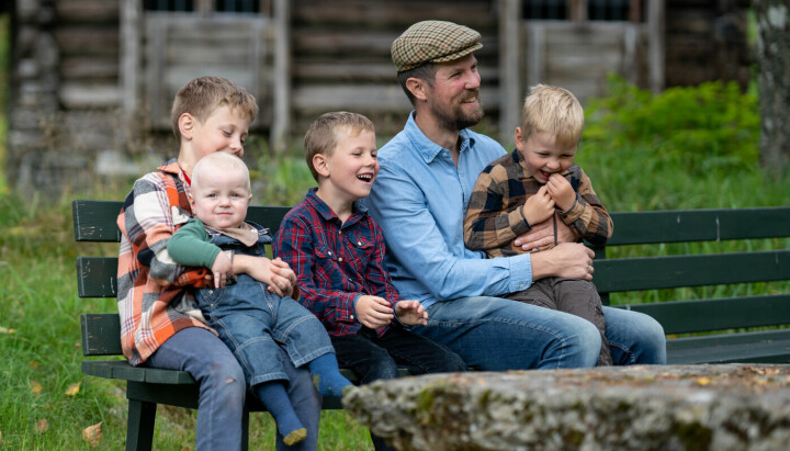 En far med fire sønner som sitter på en benk