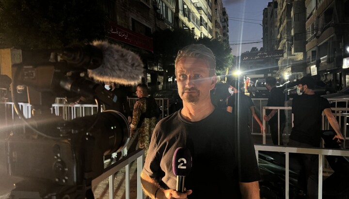 Bent Skjærstad i Beirut for å dekke Israels angrep på Libanon. Mann ser inn i et filmkamera mens han holder en mikrofon.