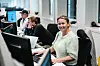 Blid kvinne som sitter ved pulten sin på kontoret