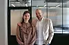 To personer står side om side foran en glassvegg i et moderne kontor