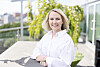 Heidi Odde Karstensen står utendørs foran en glassfasade i hvit skjorte.