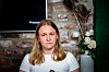 Hanna Oftedal Negård foran en murvegg, med skjerm og blomster i bakgrunnen.